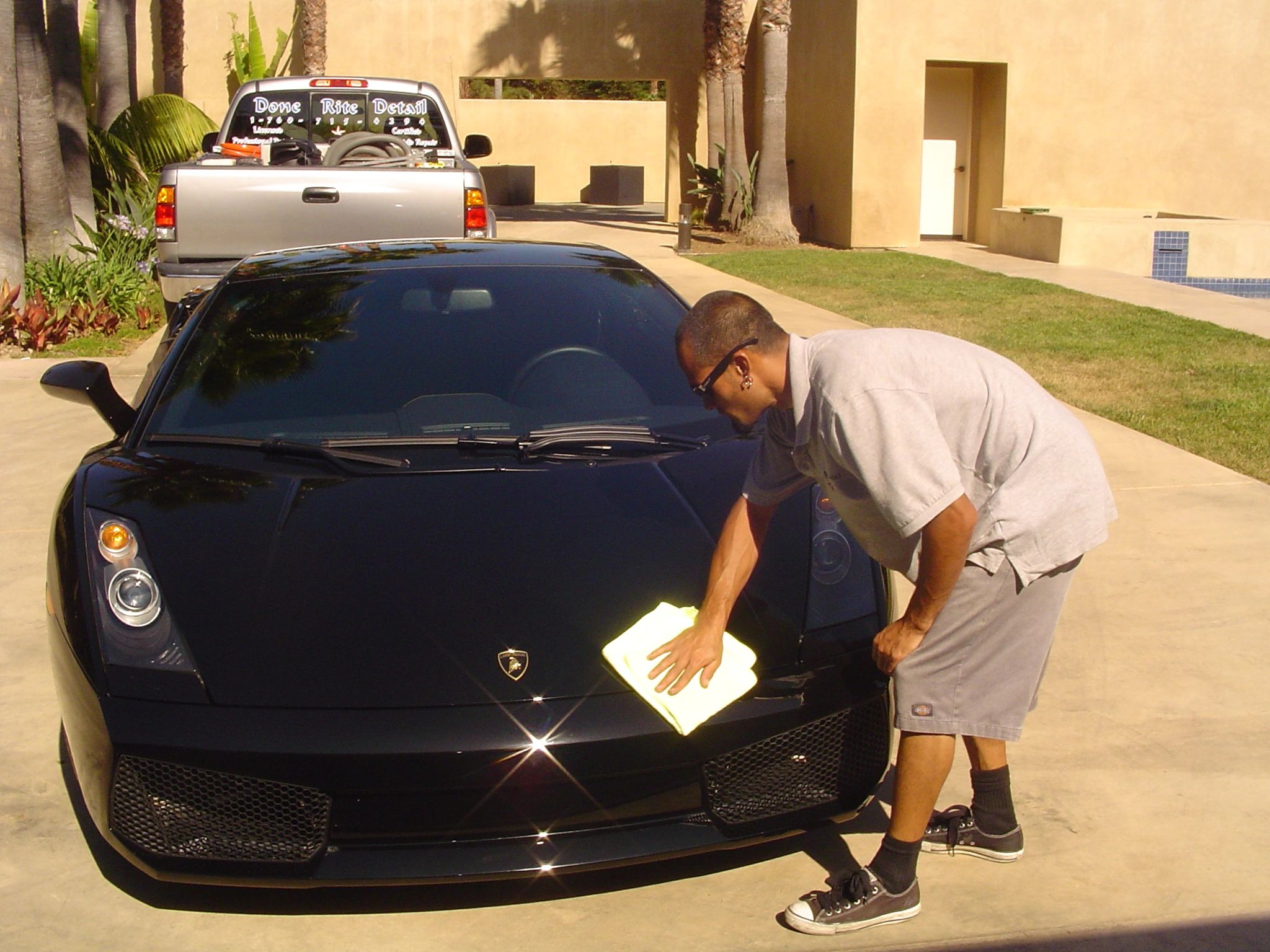 Detailer working on a Lamborghini in a residential driveway